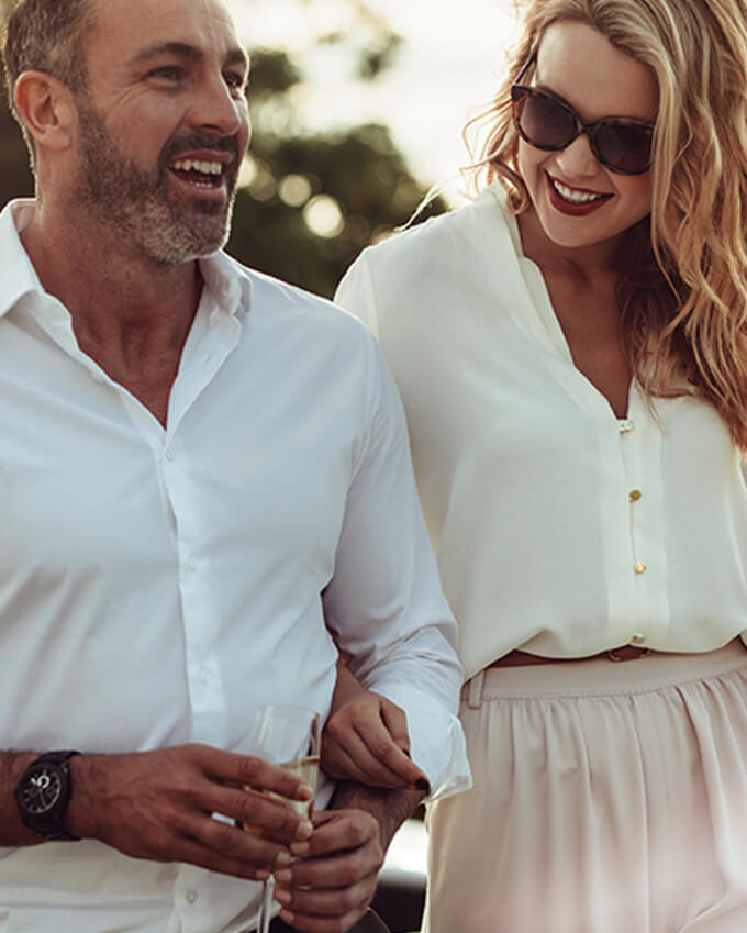 couple dress in neutral tones having drinks at sunset
